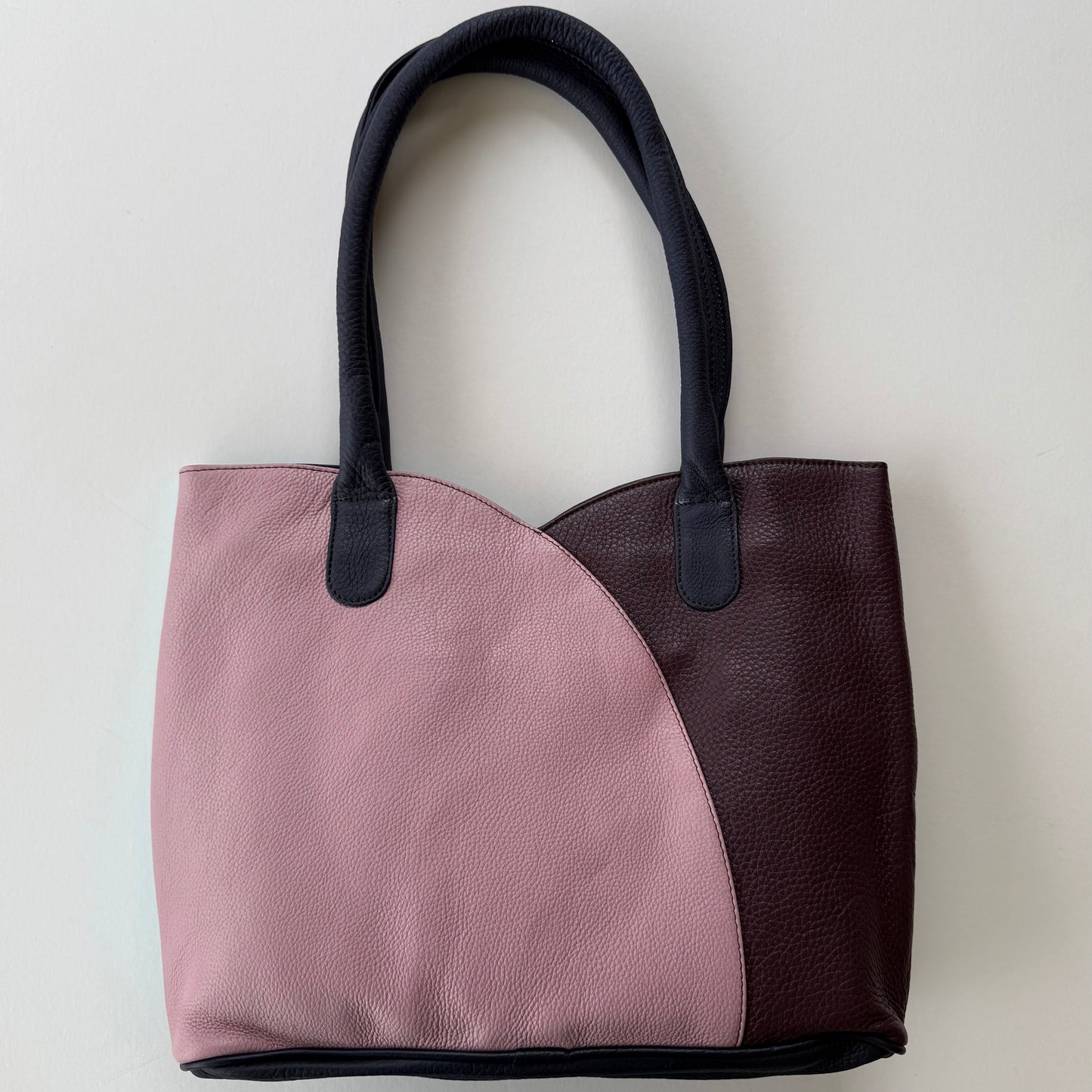 Two-toned tote bag with pink and maroon sections on a light gray background