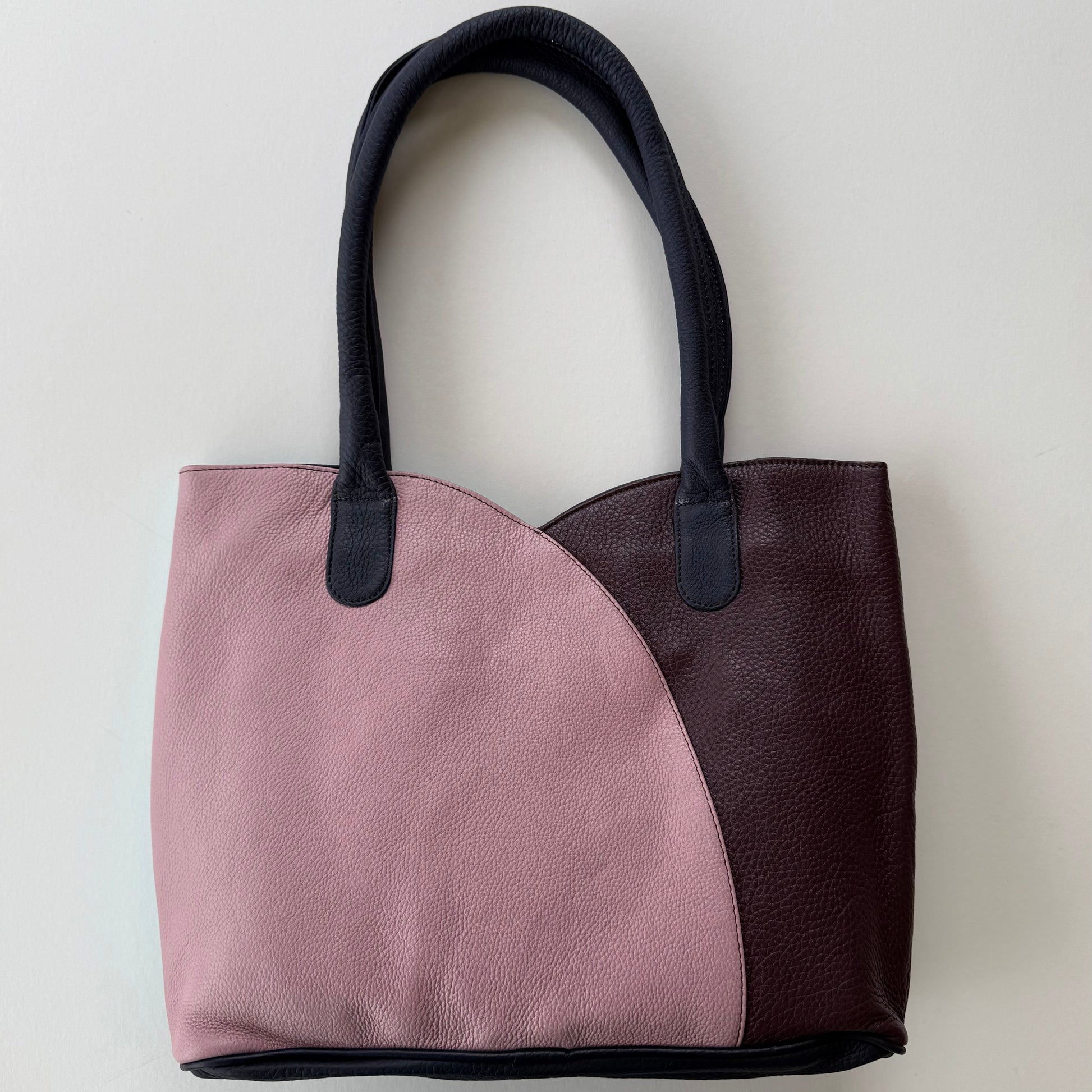 Two-toned tote bag with pink and maroon sections on a light gray background