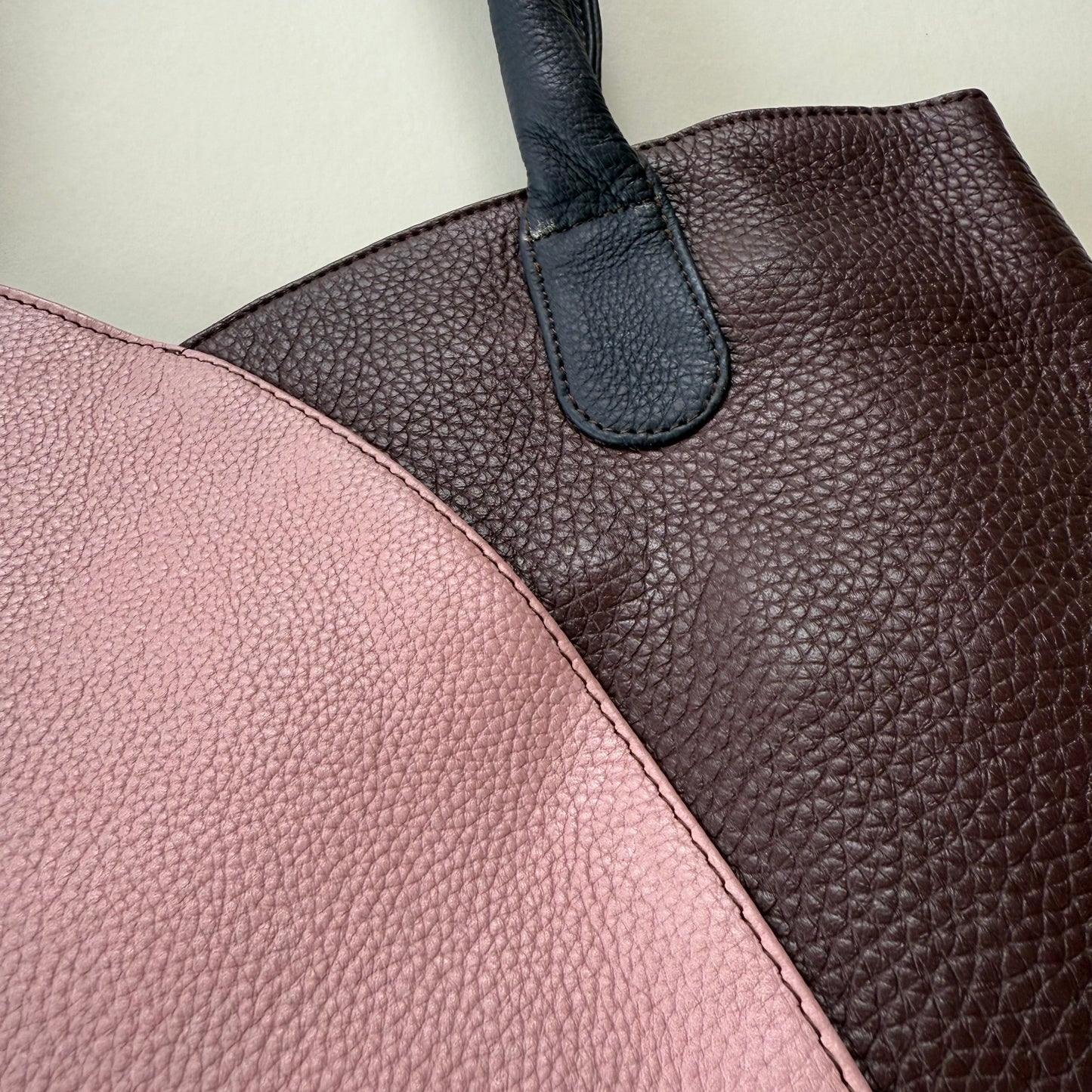 Close-up of a leather handbag with pink and brown sections.