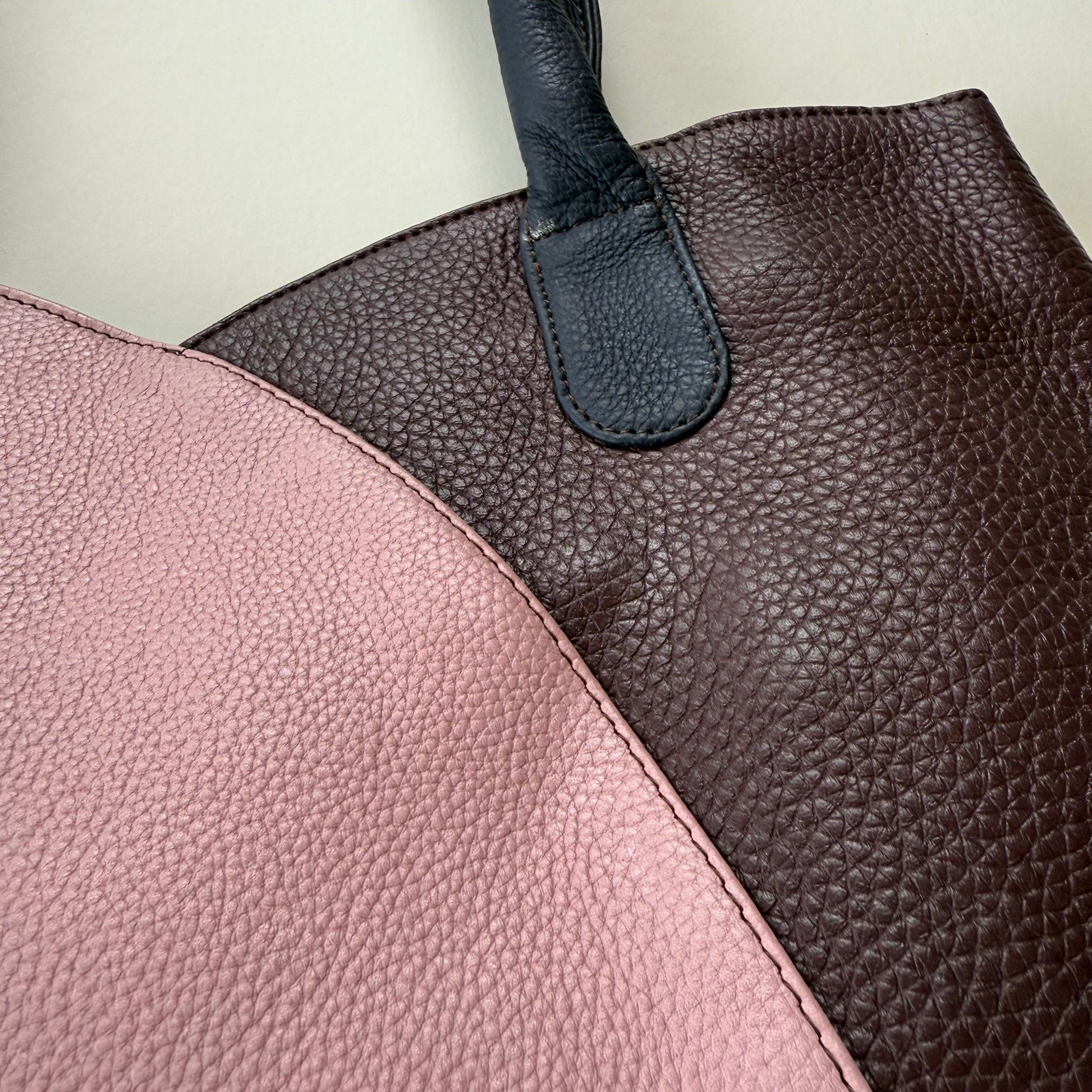Close-up of a leather handbag with pink and brown sections.