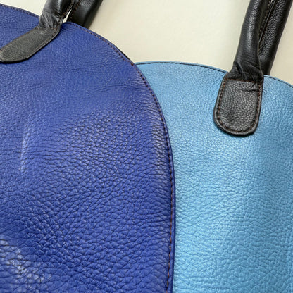 Close-up of a blue leather bag with a black strap.