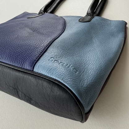 bottom view of Blue and black leather handbag on a light background