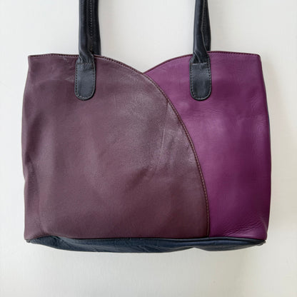 Two-tone purple handbag with black handles on a white background