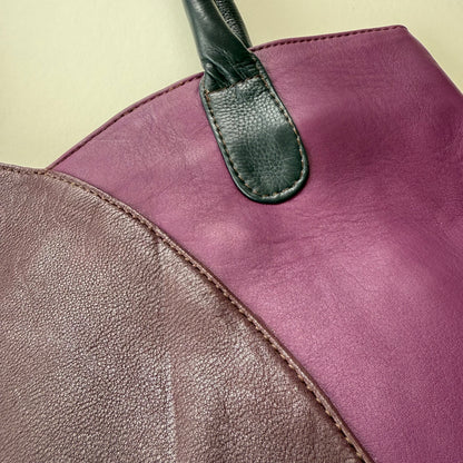 Close-up of a leather handbag with 2 purple sections on a beige background