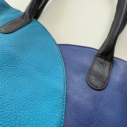 Close-up of a blue and black leather handbag on a light background