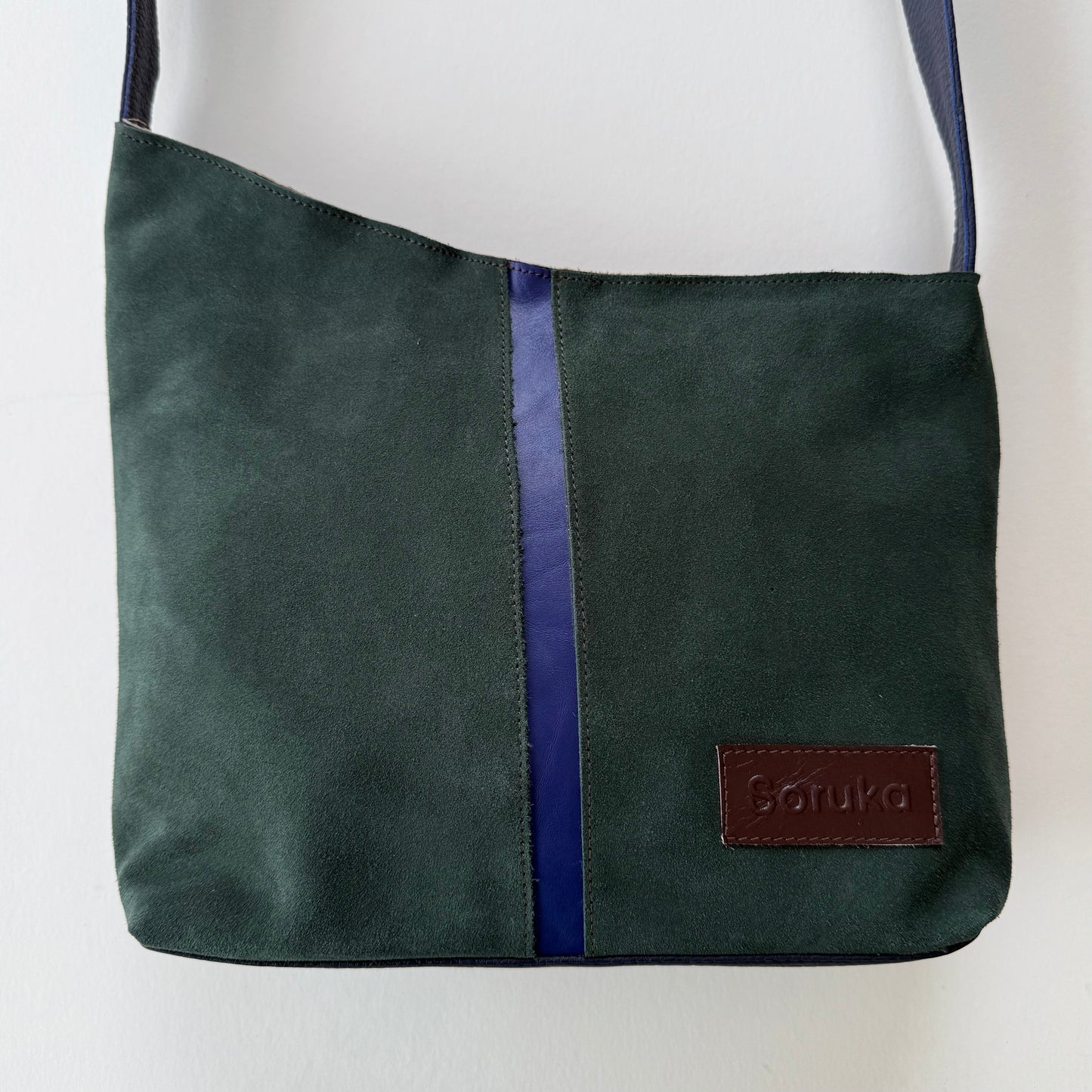 green suede shoulder bag with purple stripe down the middle