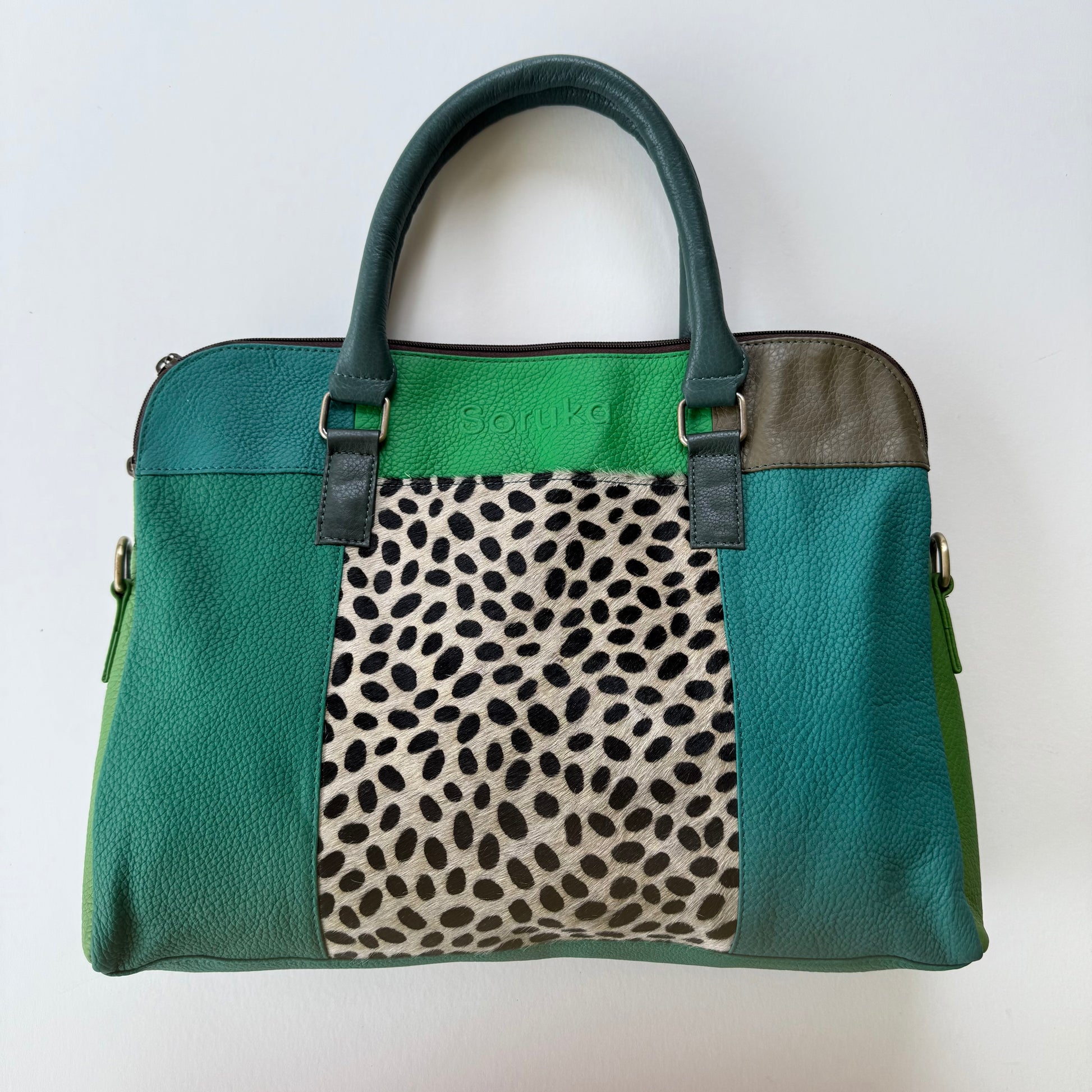 Green patchwork handbag with a animal print section on a white background
