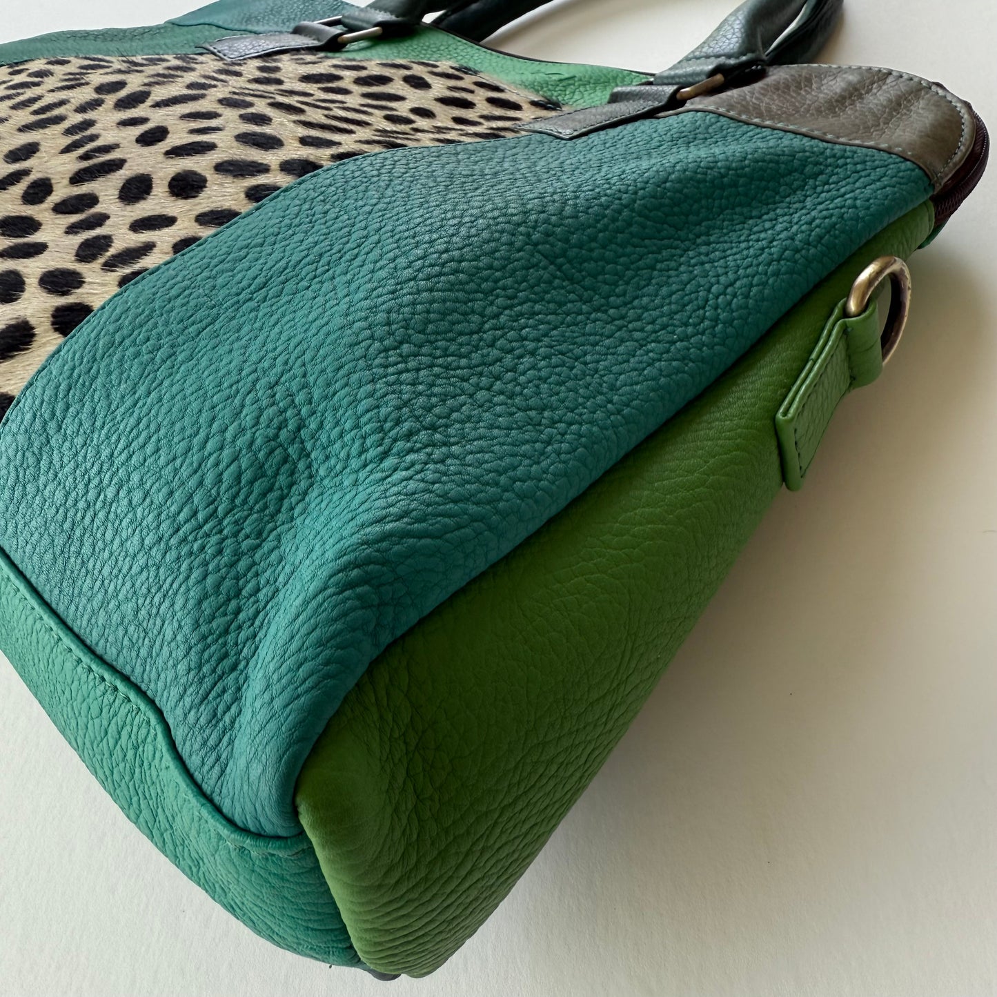 side view of Green handbag with leopard print pattern on a white background