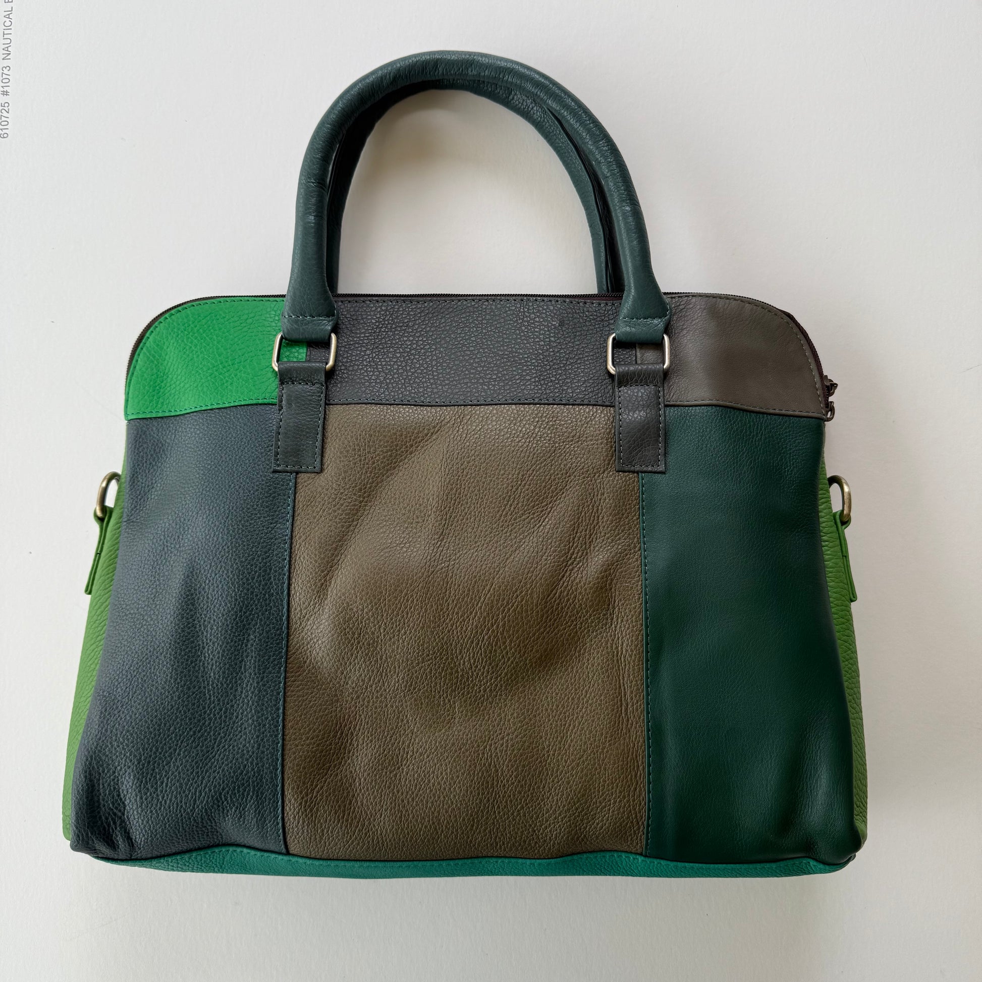 back view of Multicolored handbag with green, brown, and black sections on a light gray background