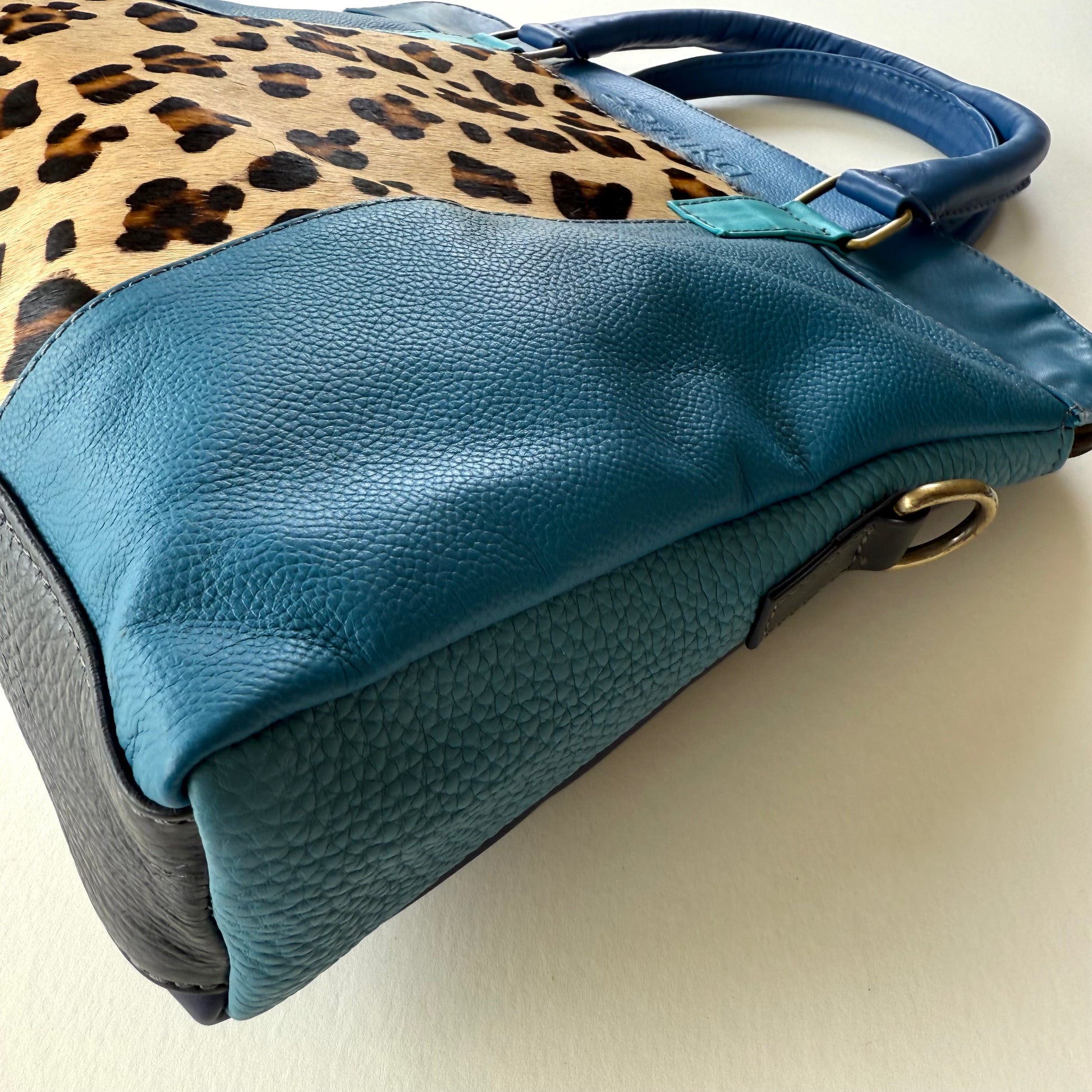 side view of Blue handbag with leopard print pattern on a light background