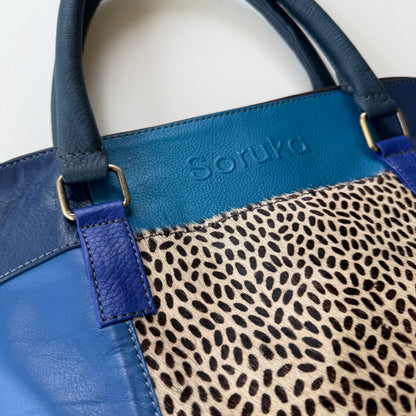 close-up of Blue handbag with a leopard print pocket on a white background