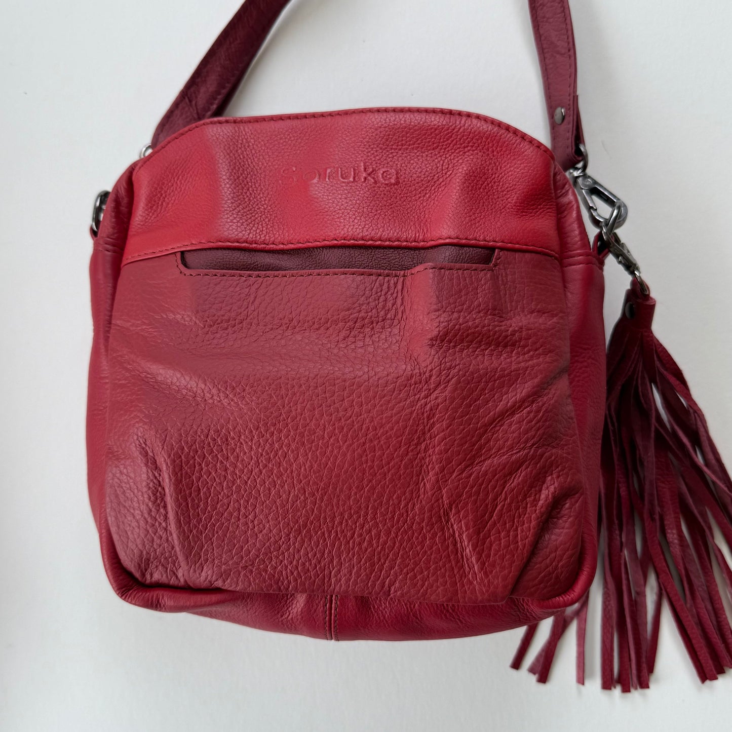 Red leather handbag with a tassel on a white background