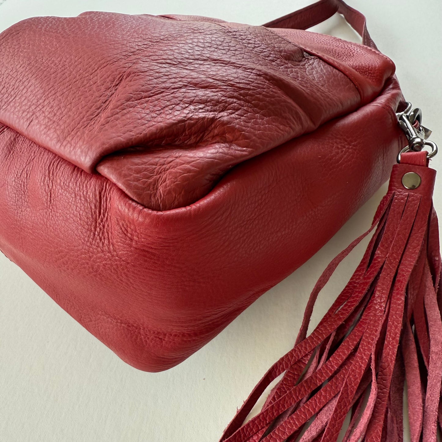 bottom view of Red leather handbag with a tassel on a light background