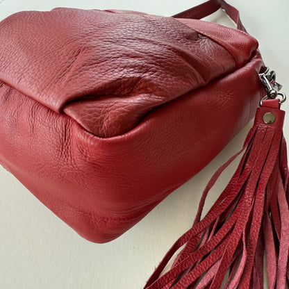 bottom view of Red leather handbag with a tassel on a light background