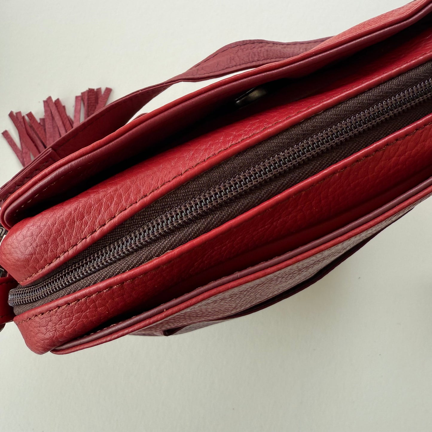 top view of red leather handbag showing zipper closure and pockets
