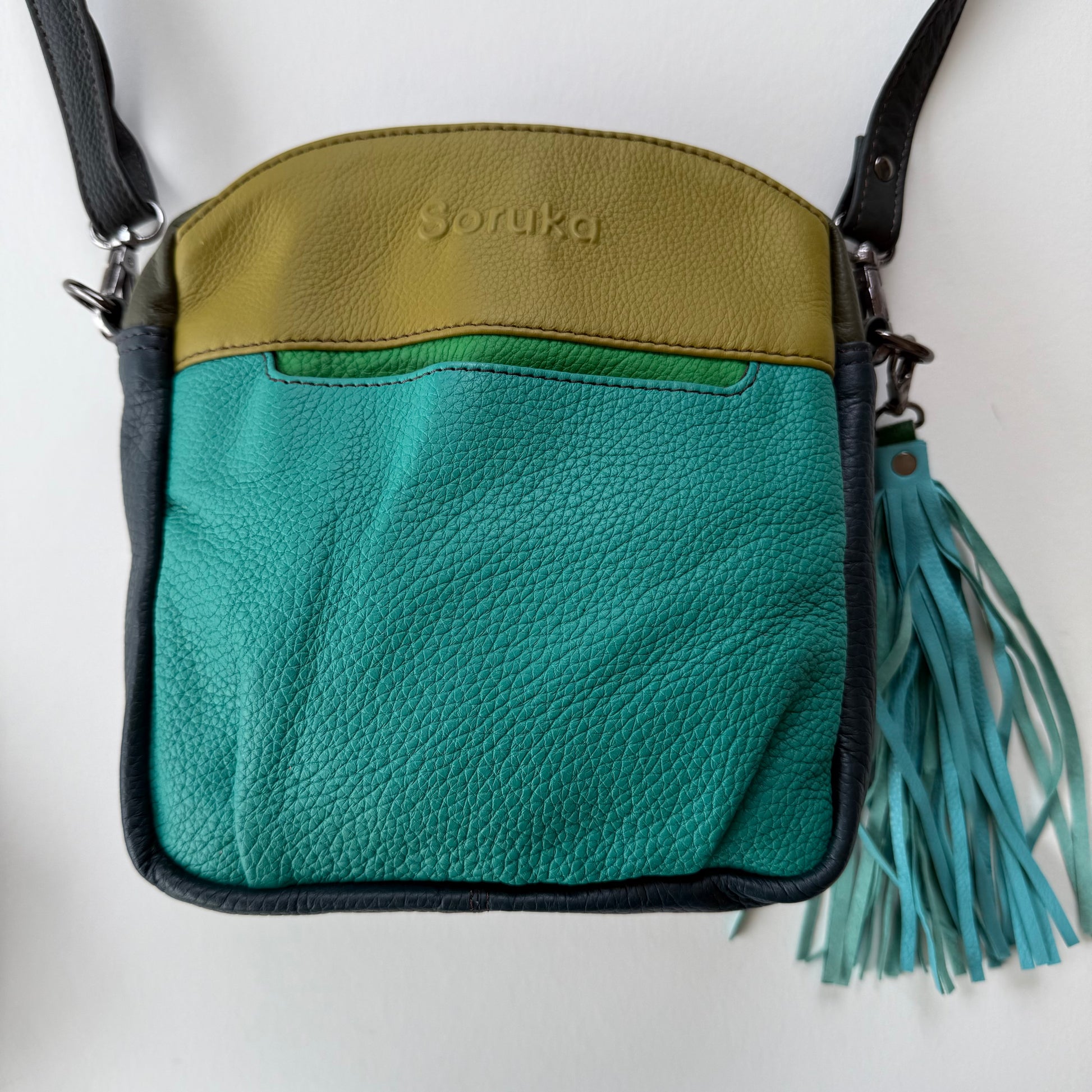 turquoise leather crossbody bag with tassel on a white background