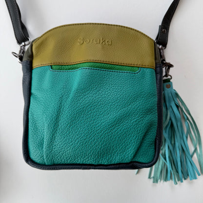 turquoise leather crossbody bag with tassel on a white background