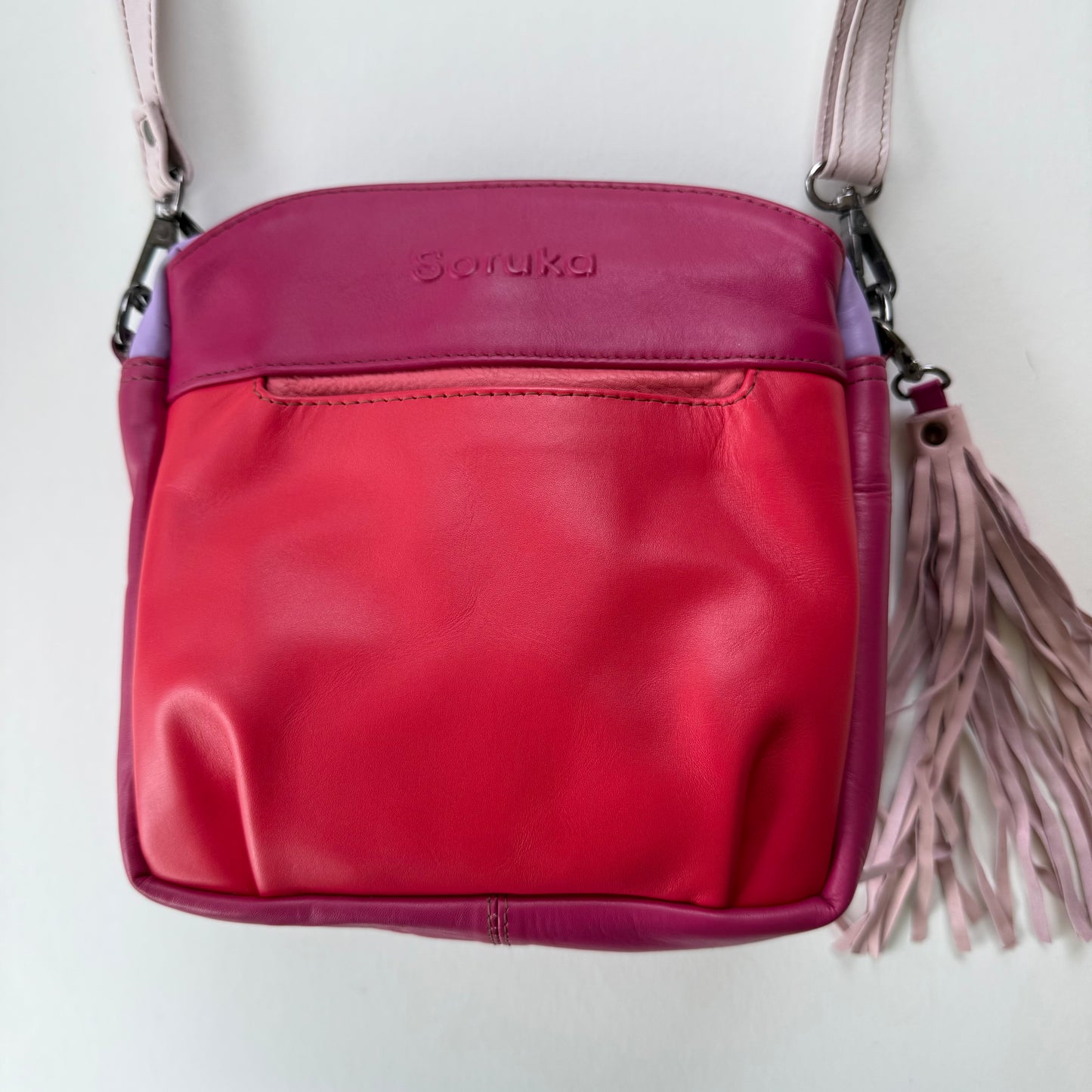 handbag in various shades of pink with a light pink tassel