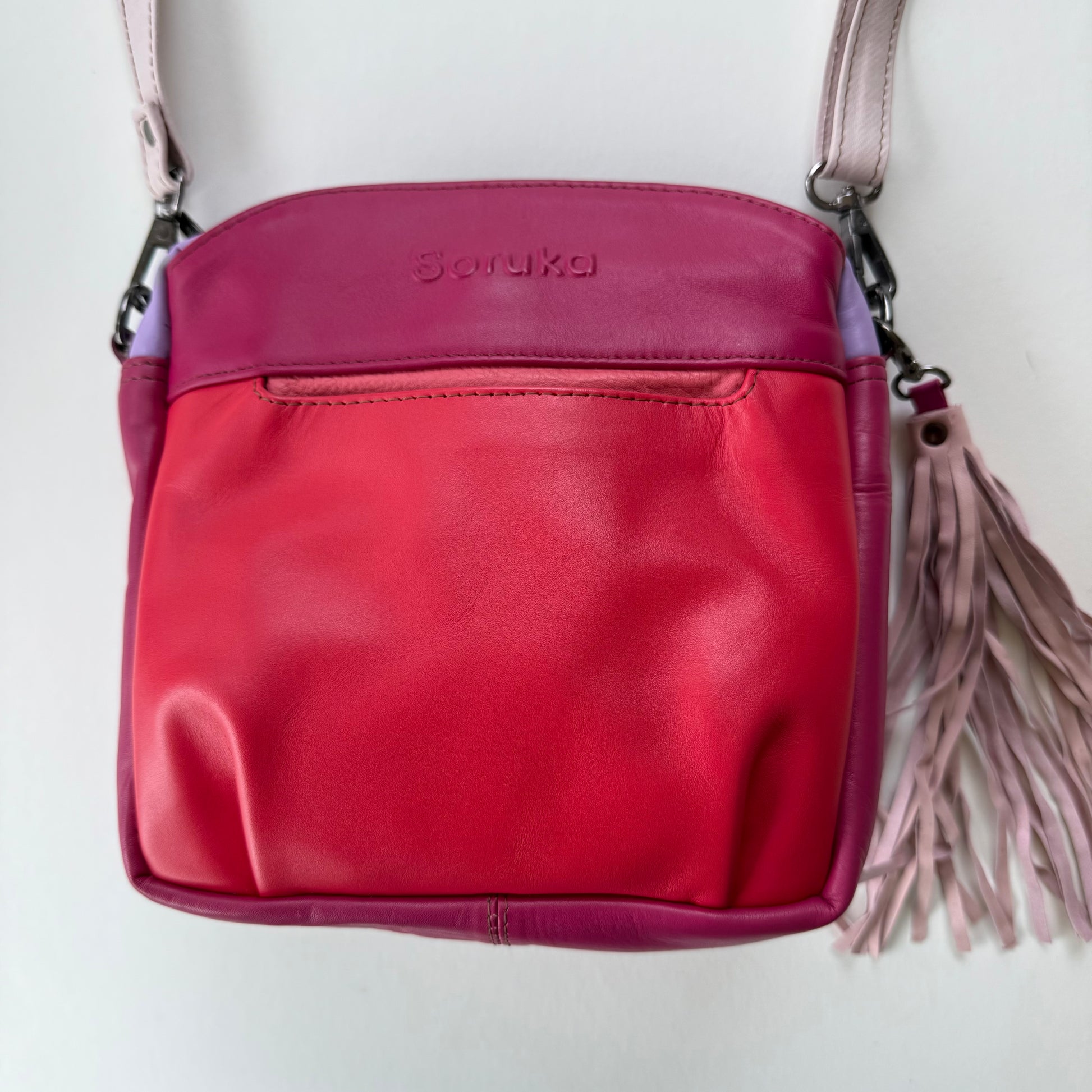 handbag in various shades of pink with a light pink tassel