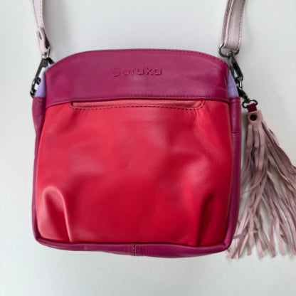 handbag in various shades of pink with a light pink tassel
