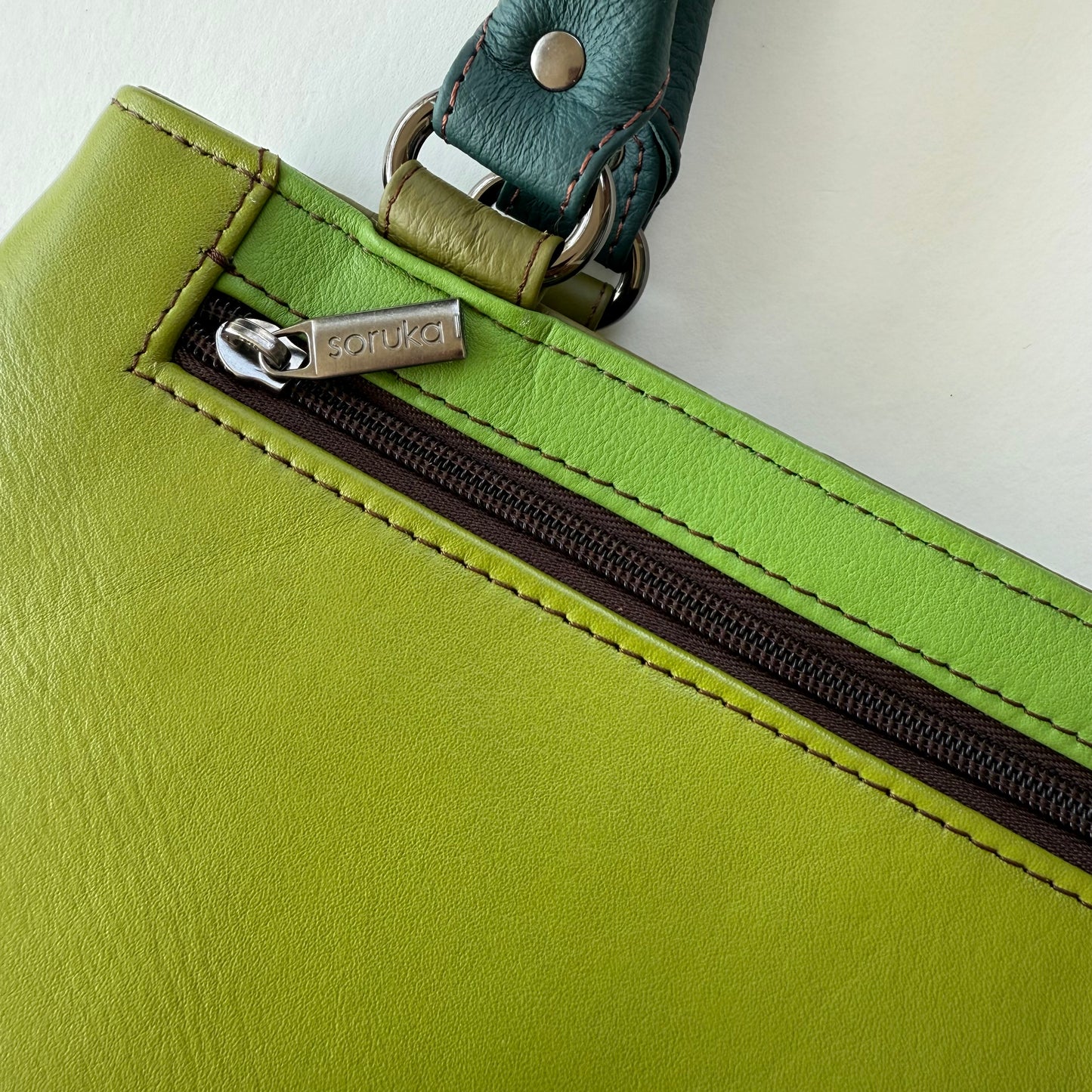 Close-up of a green leather bag with a zippered pocket