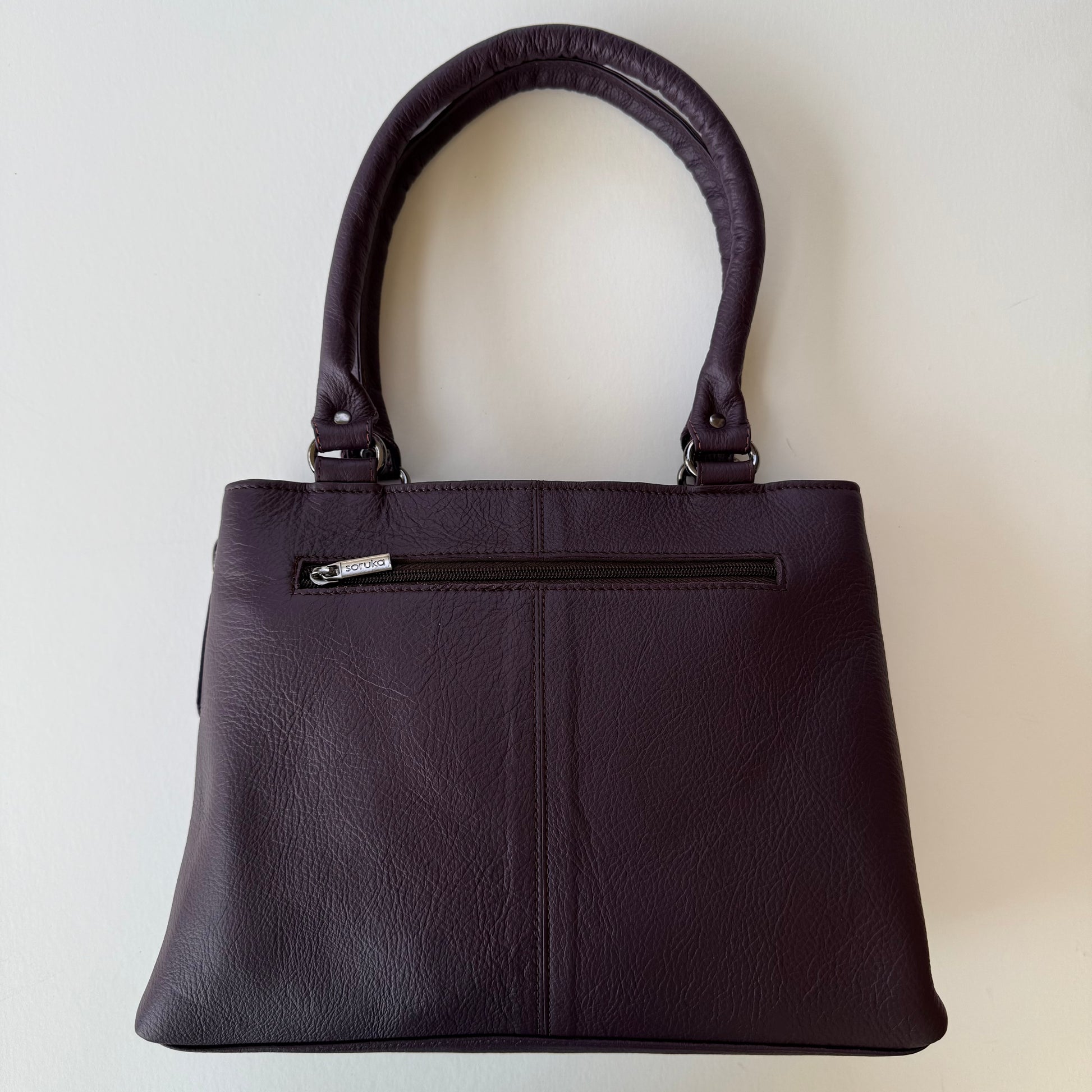 back view of handbag with deep purple leather backing