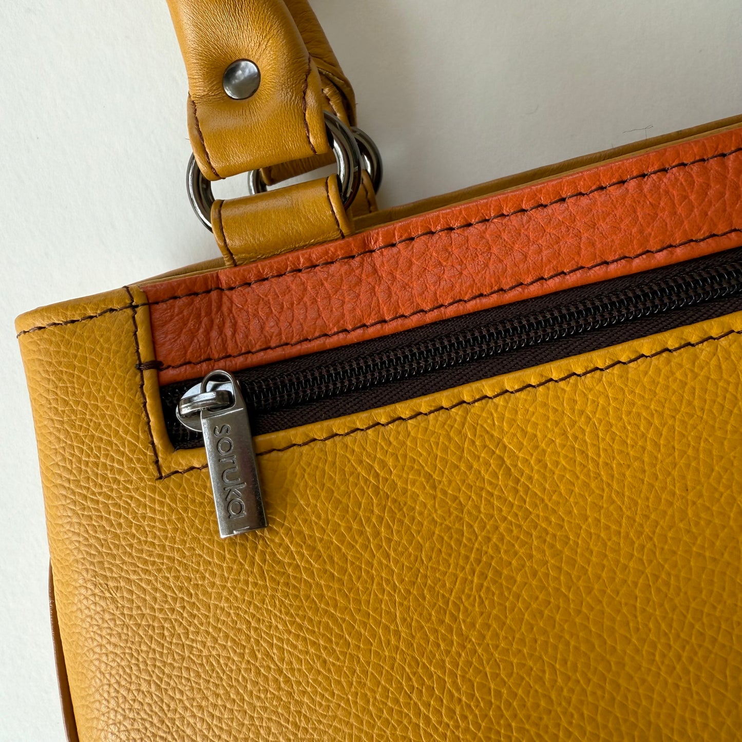 close-up of yellow and orange handbag with zipper pocket
