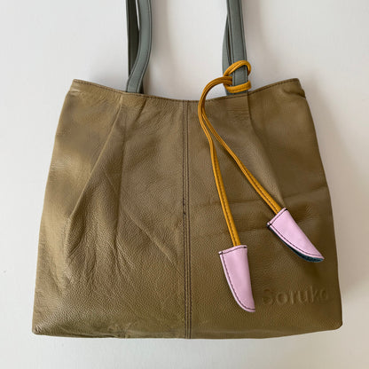 sandy beige tote bag with a yellow and pink accent tassel on a white background