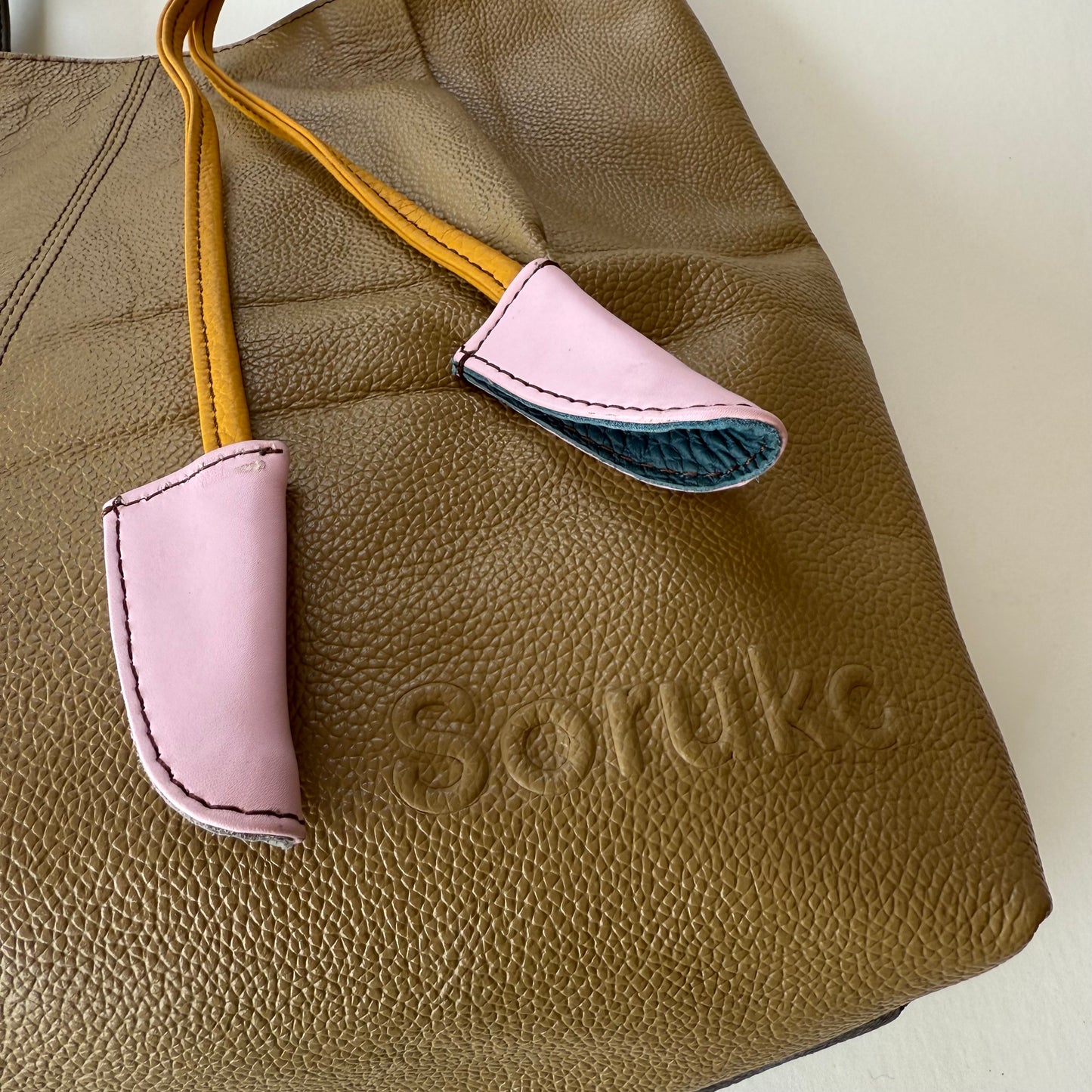 close-up of sand colored tote and pink and yellow tassel