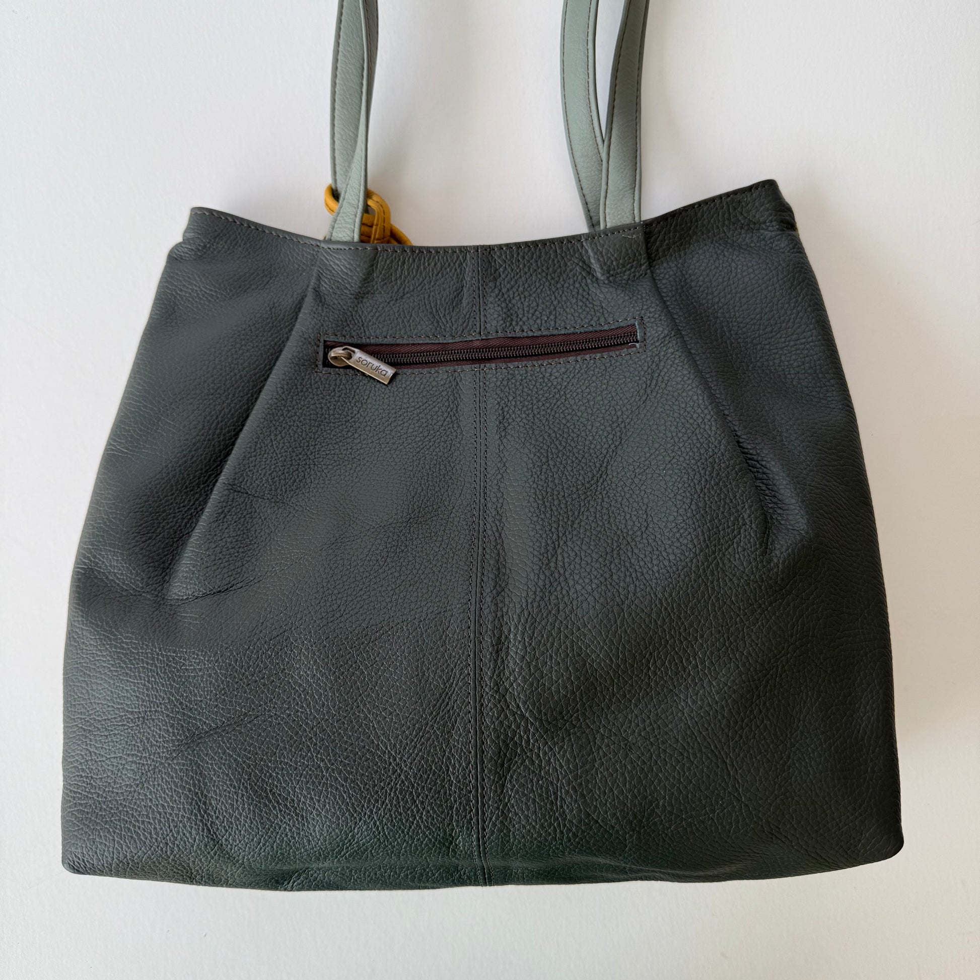 back view of tote with Dark gray leather and a zipper pocket on a light background