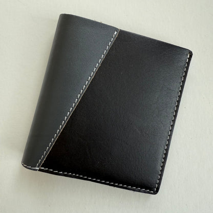 Black and grey leather wallet with white stitching on a light gray background