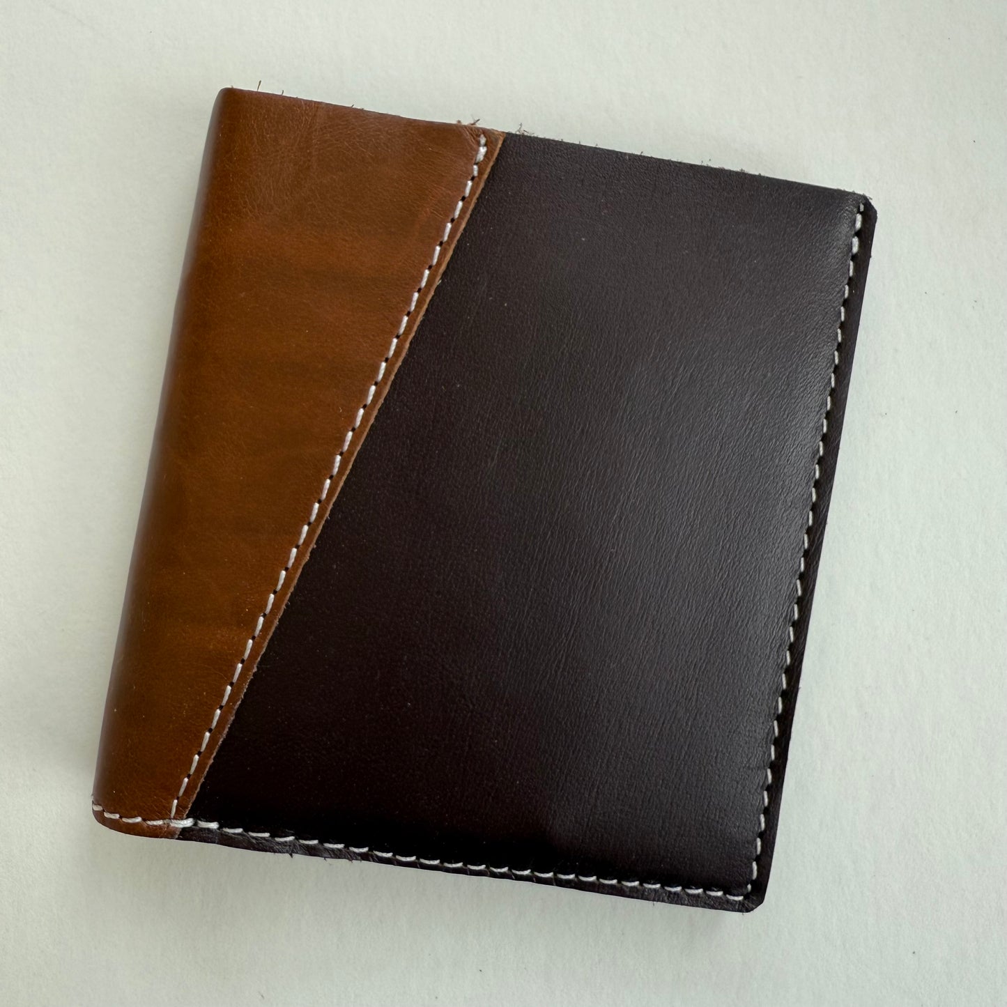 Two-tone brown leather wallet on a light gray background