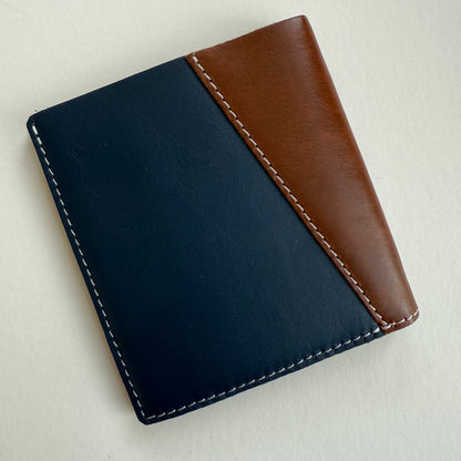Two-tone navy and brown leather wallet on a light beige background