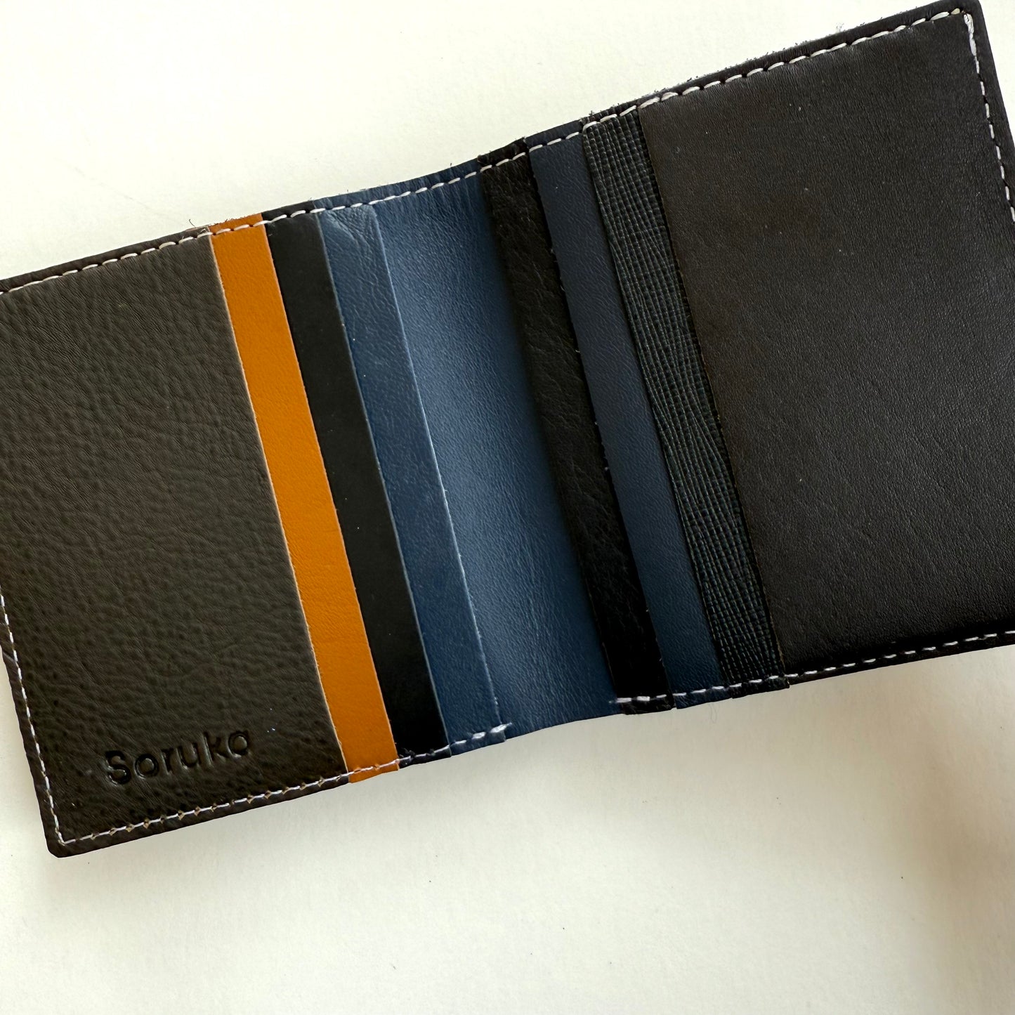 interior view of Black leather wallet with multi-colored card slots on a white background