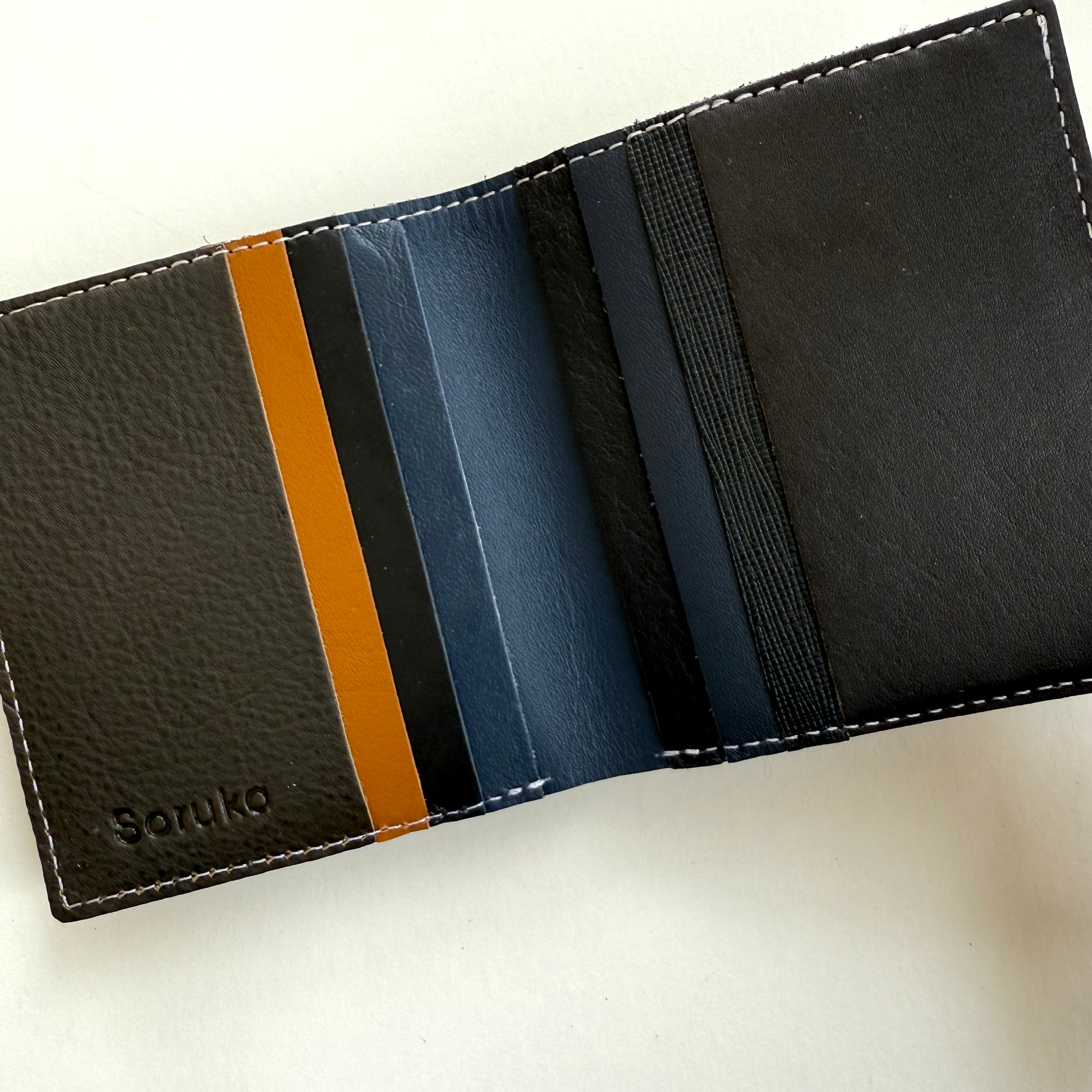 interior view of Black leather wallet with multi-colored card slots on a white background
