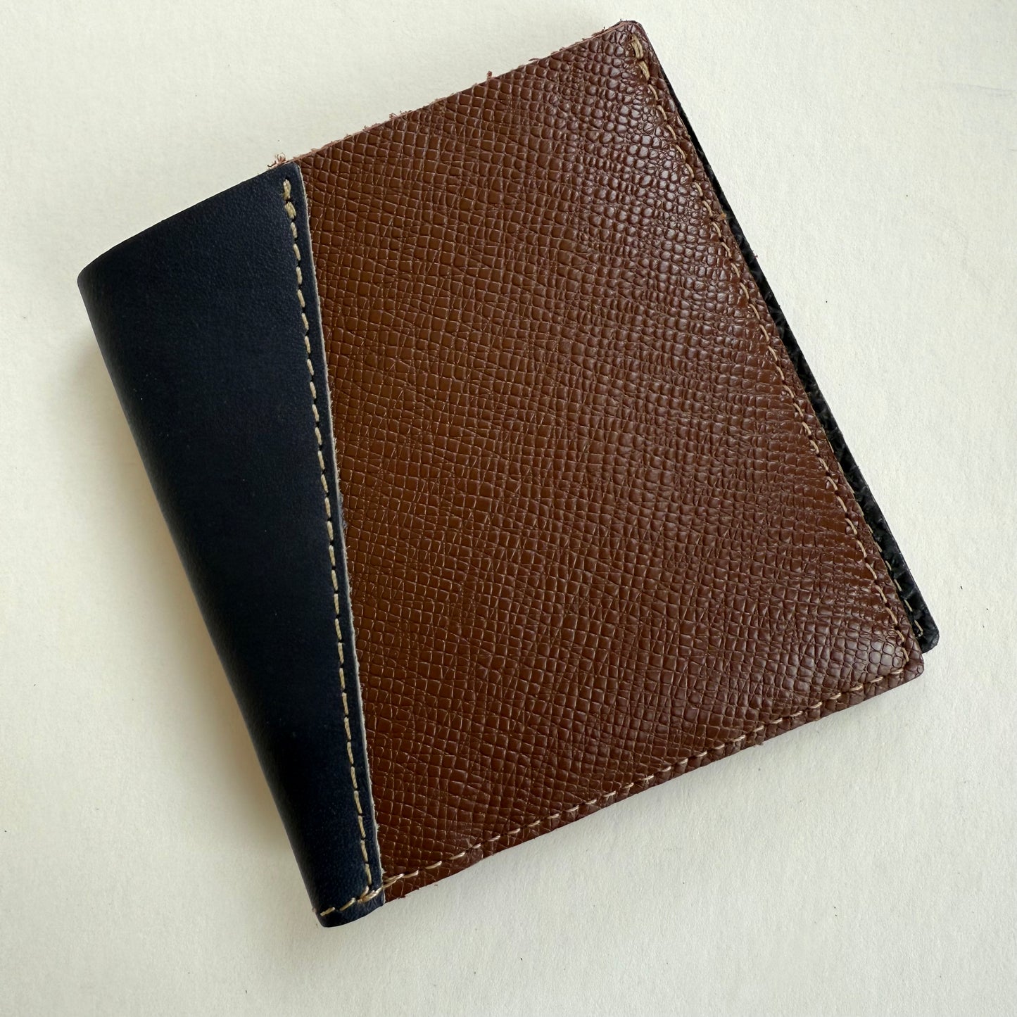 Two-tone brown and DARK NAVY leather wallet on a light beige background