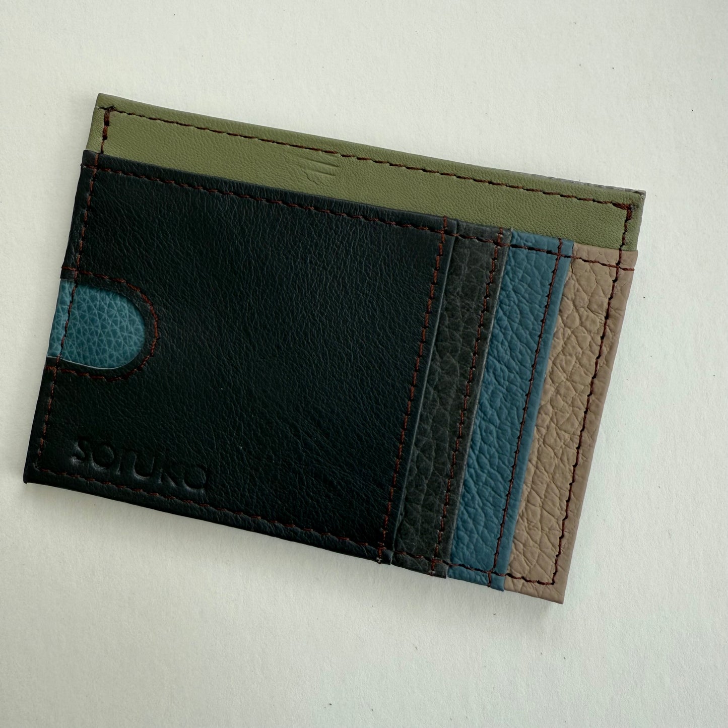 brown, blue, and green leather wallet  on a light gray background
