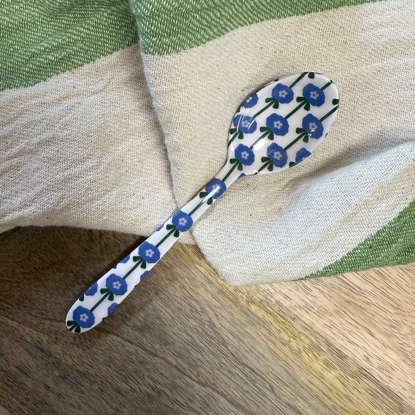 small spoon with blue floral pattern on a wood surface with a kitchen towel.