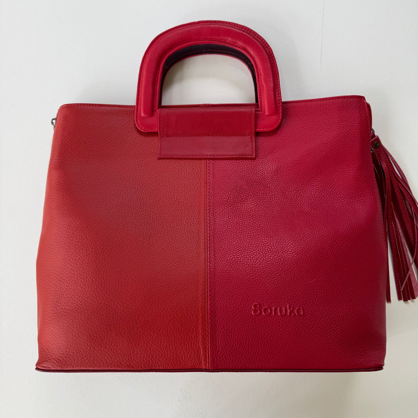 Red tote bag with a tassel on a white background