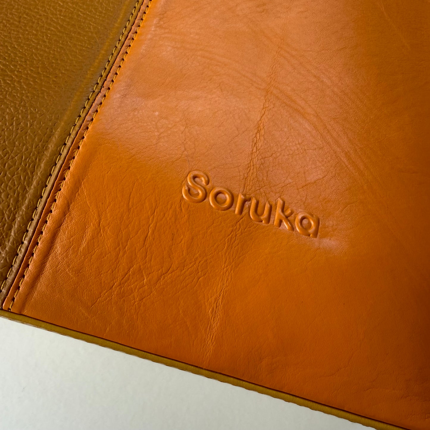 bottom corner of yellow-brown tote bag with 'soruka' logo