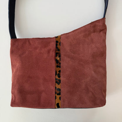 muted burgundy handbag with leopard print accent on a white background
