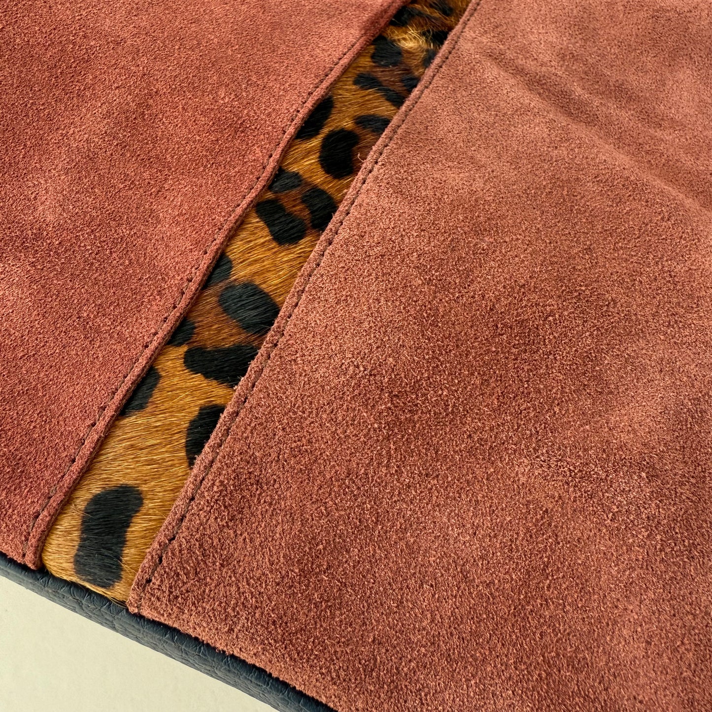 Close-up of a light burgundy bag with a leopard print pattern accent down the middle.