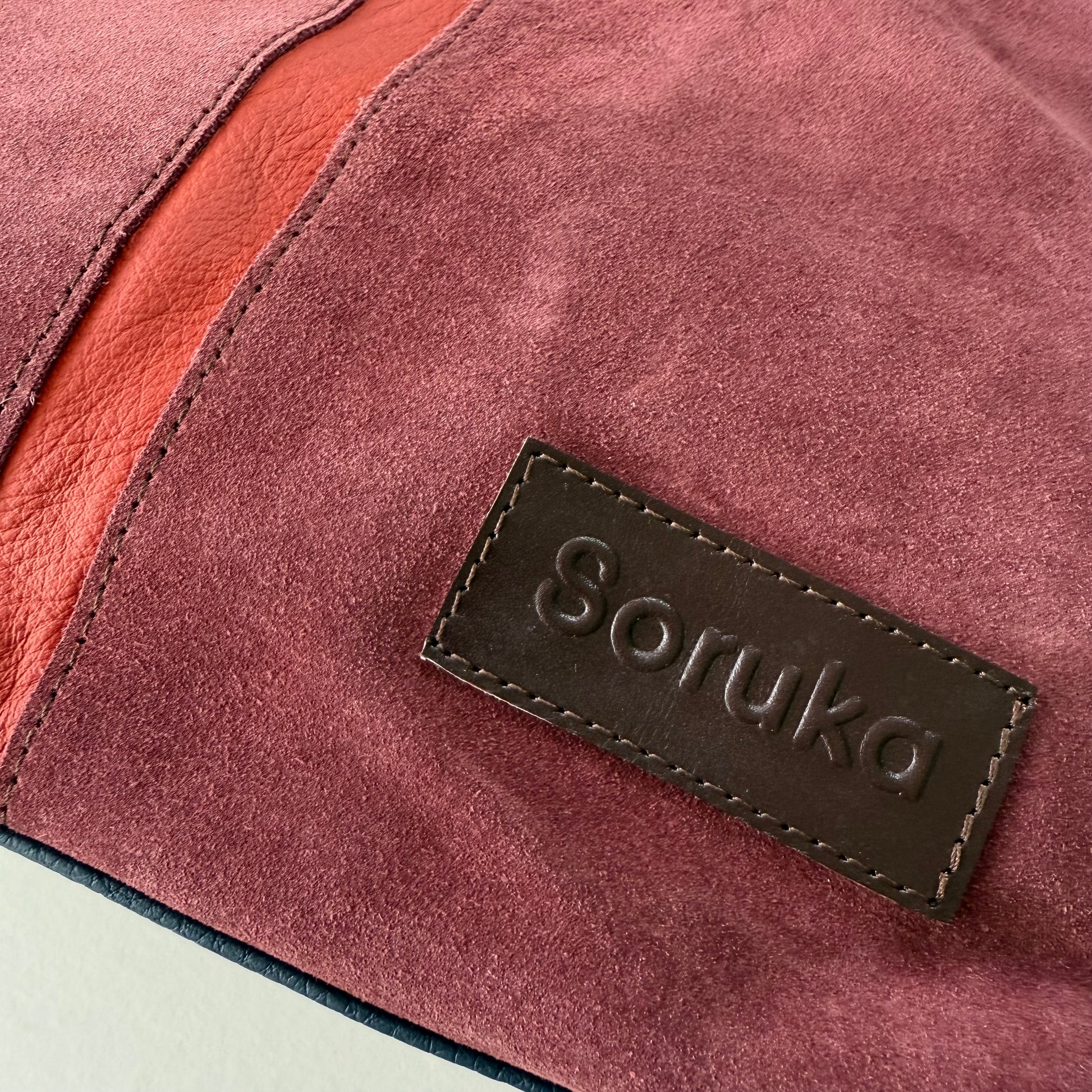 Close-up of a maroon suede bag with 'Soruka' branding.
