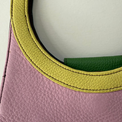 Close-up of a pink leather bag with round yellow handle