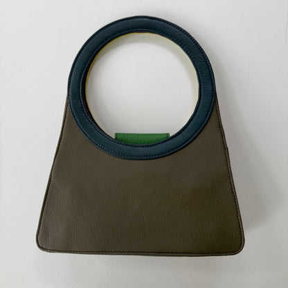 back view of Green handbag with a blue circular handle on a white background