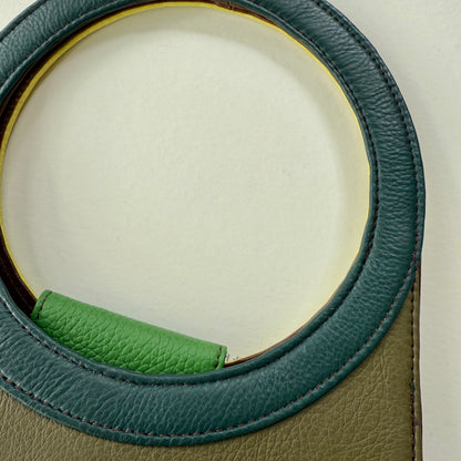Close-up of a green handbag with round blue handle