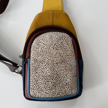 Sling bag in a patch work of colors with spotted pattern front pocket