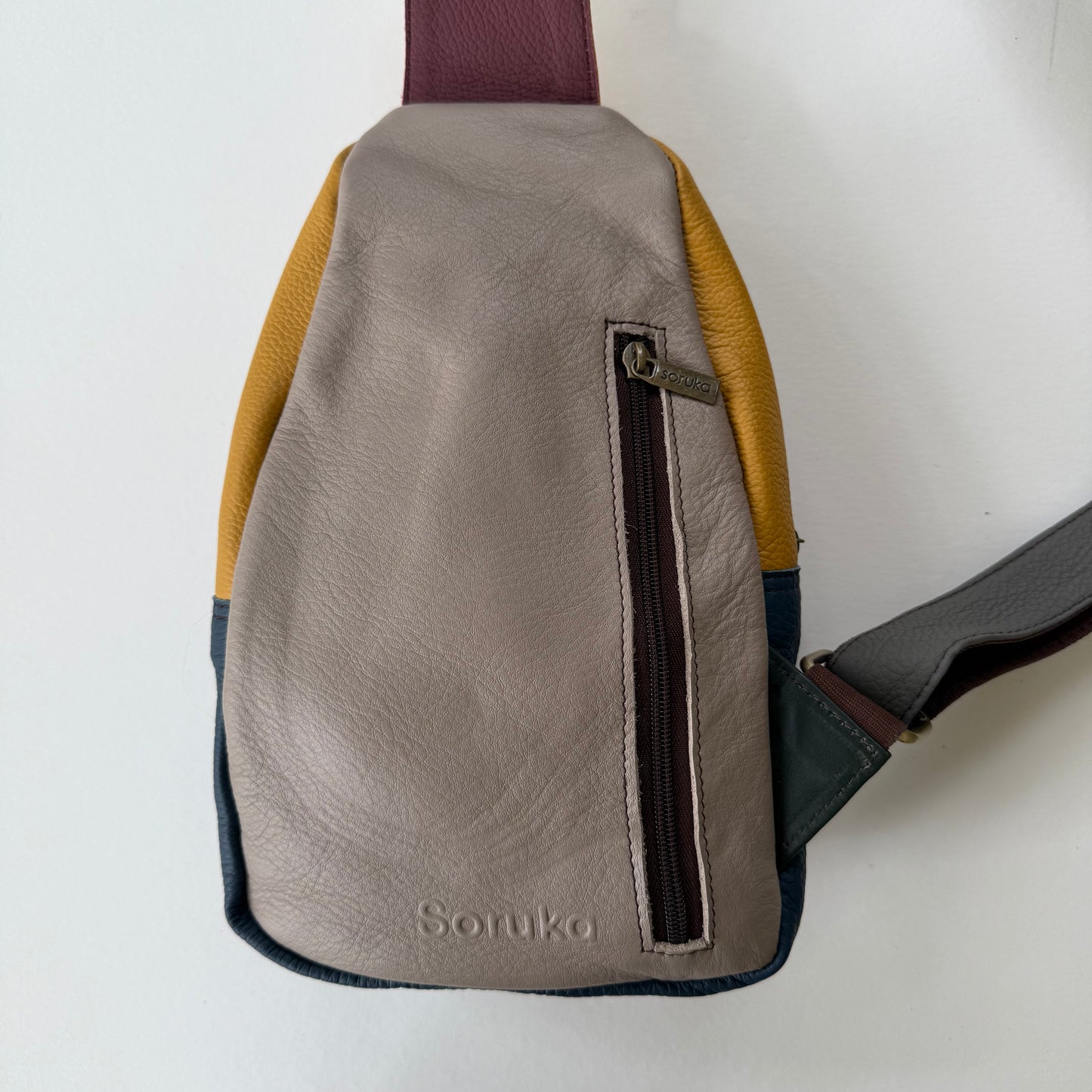 back view of grey sling bag with zippered pocket