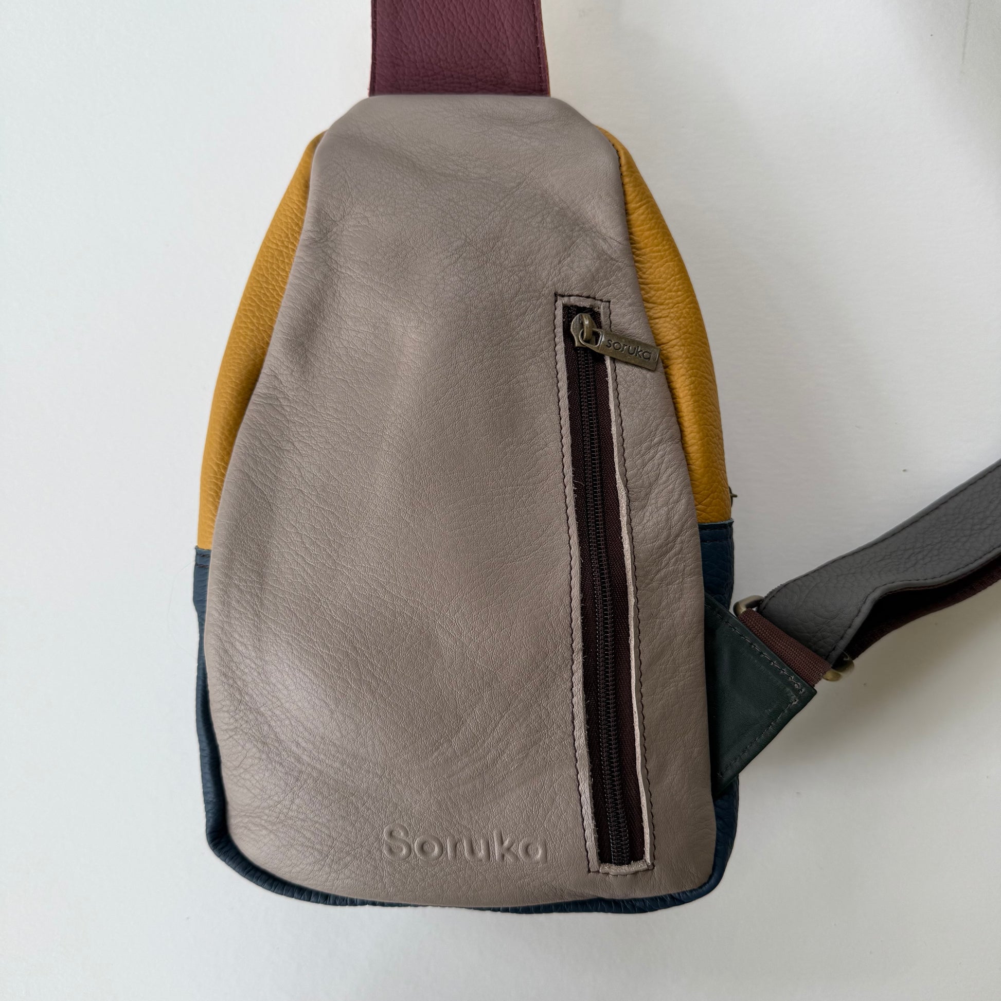 back view of grey sling bag with zippered pocket