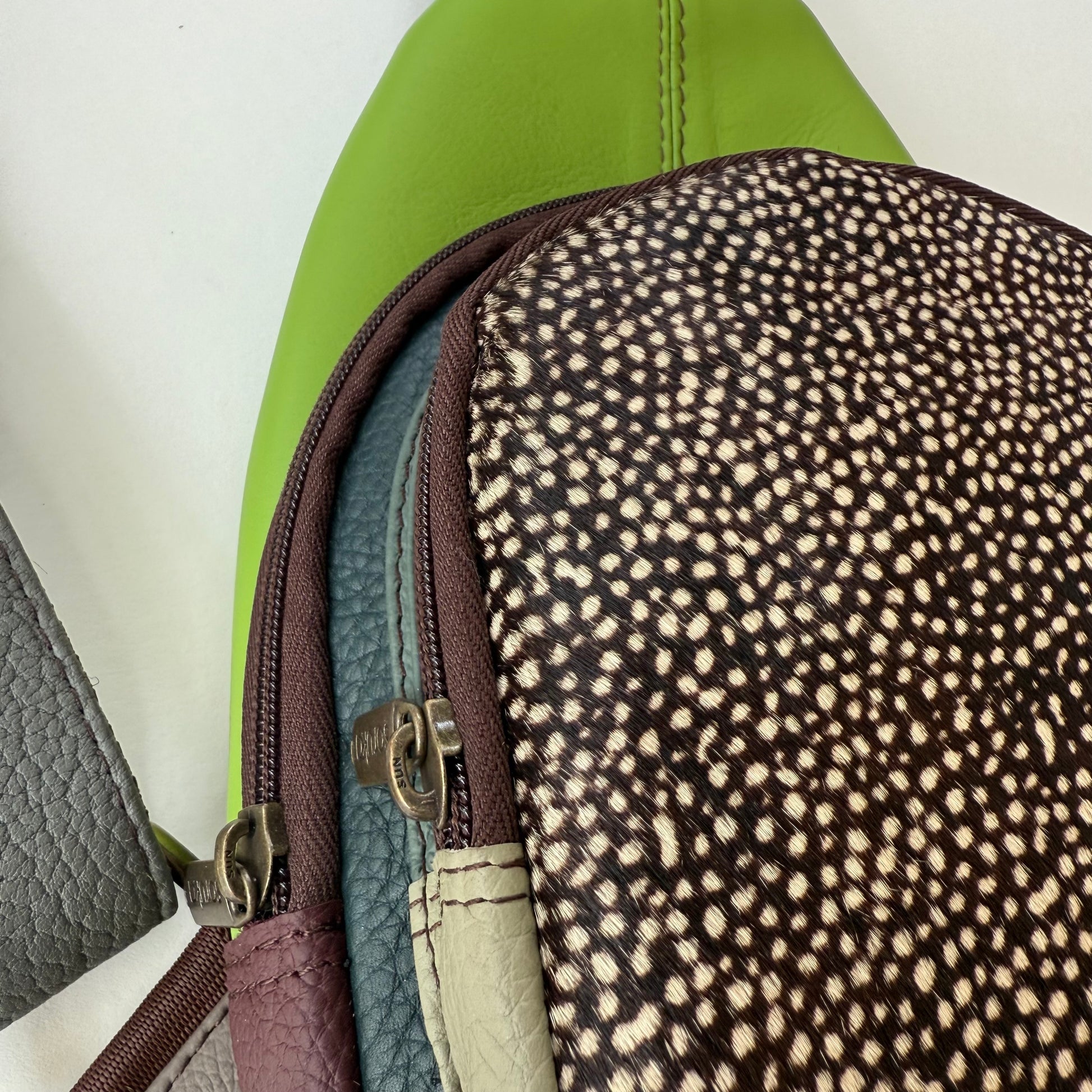 Close-up of a multi-colored sling bag showing 2 zipper compartments